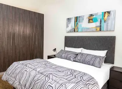 a bedroom with a bed with a black and white comforter at Century On Lake Apartment in Cape Town