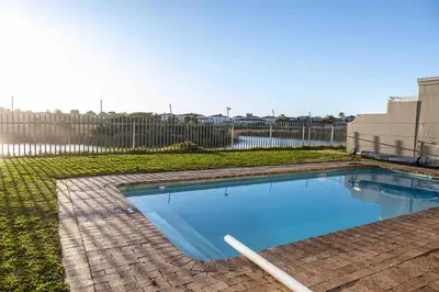 a swimming pool in a yard with a fence at Century On Lake Apartment in Cape Town