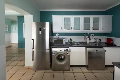 a kitchen with a refrigerator and a washing machine at 'Harbour Views' - 2 bedroom, sleeps 4 with private pool and large veranda! in Gordonʼs Bay