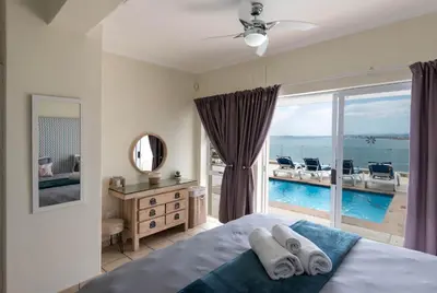 a bedroom with a bed and a view of a pool at 'Harbour Views' - 2 bedroom, sleeps 4 with private pool and large veranda! in Gordonʼs Bay