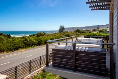 a balcony with a view of a road and the ocean at Grandeur in Hermanus
