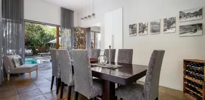 a dining room with a table and chairs and a pool at Two Bedroom Soutpan Apartment in Hermanus