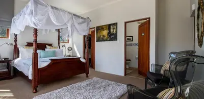 a bedroom with a canopy bed and a chair at Two Bedroom Soutpan Apartment in Hermanus