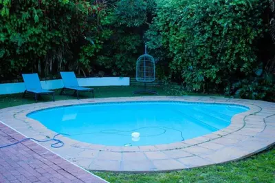 a swimming pool with two chairs and a bird cage at 3 on The Fairway Pinelands in Cape Town