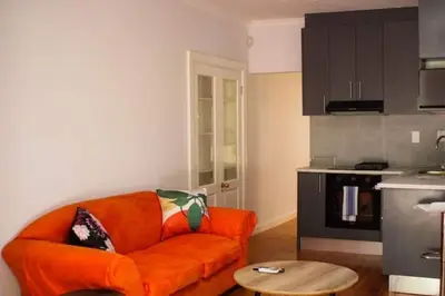 a living room with an orange couch and a kitchen at 3 on The Fairway Pinelands in Cape Town