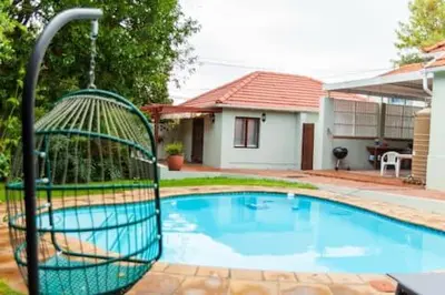a bird cage sitting next to a swimming pool at 3 on The Fairway Pinelands in Cape Town