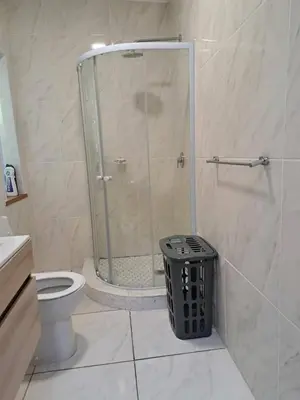a bathroom with a shower with a toilet and a trash can at 3 on The Fairway Pinelands in Cape Town