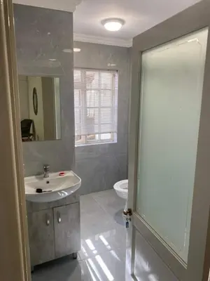 a bathroom with a sink and a mirror and a toilet at 3 on The Fairway Pinelands in Cape Town