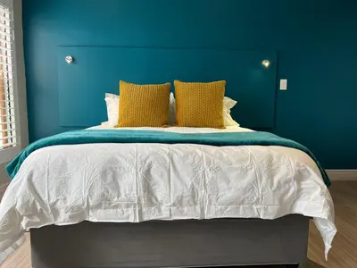 a blue bedroom with a large bed with yellow pillows at Hermanus Waterfront Apartment no 17 in Hermanus