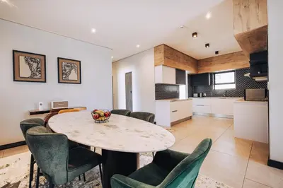 a kitchen and dining room with a table and chairs at Phoenix Home in Cape Town