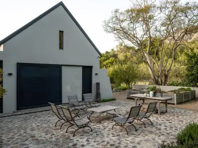 a patio with chairs and tables and a building at Farm Keerweer in Stellenbosch
