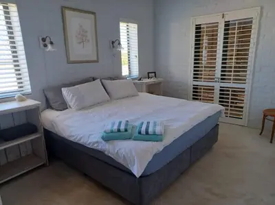 a bedroom with a large bed with two pillows on it at Chillilabombwe in Pringle Bay