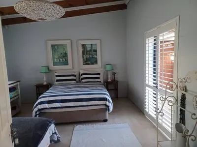 a bedroom with a bed and two lamps and a window at Chillilabombwe in Pringle Bay