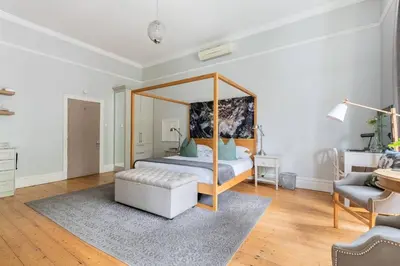 a bedroom with a canopy bed and a chair at Bonne Esperance Studio Apartments in Stellenbosch