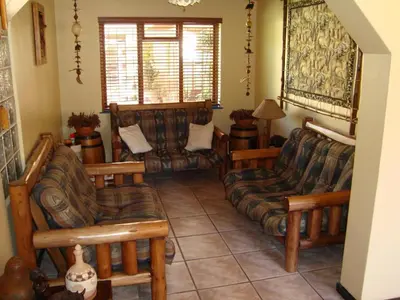 a living room with couches and chairs and a window at Pentzhaven Guesthouse in Table View