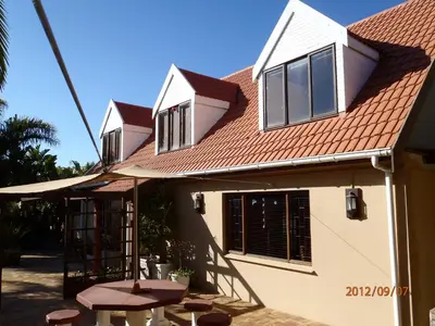 a house with a picnic table and an umbrella at Pentzhaven Guesthouse in Table View
