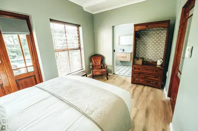 a bedroom with a bed and a dresser and a chair at Villa Chad Luxury Guesthouse in Kleinmond