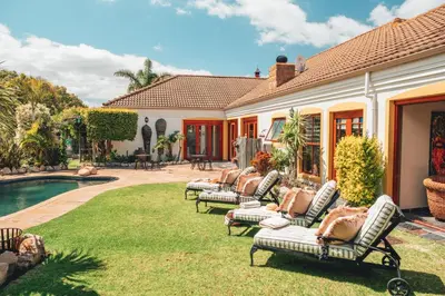 a yard with lounge chairs and a swimming pool at Villa Chad Luxury Guesthouse in Kleinmond