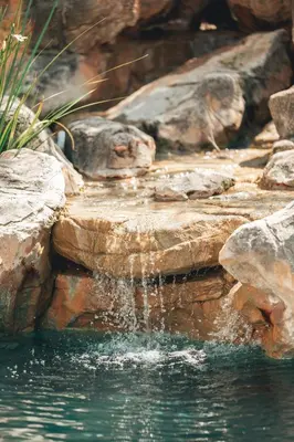 a waterfall in a pool of water with rocks at Villa Chad Luxury Guesthouse in Kleinmond