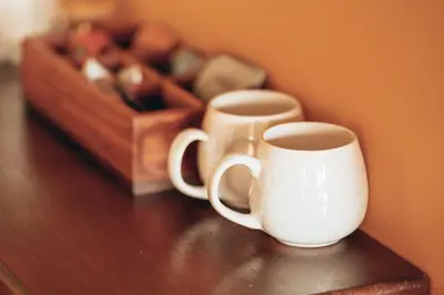 two white cups sitting on a table with a wooden box at Villa Chad Luxury Guesthouse in Kleinmond