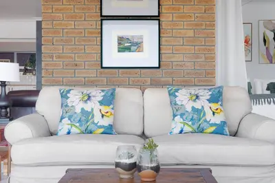 a living room with a white couch with blue pillows at Rocky Bay on the View in Gordonʼs Bay