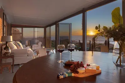 a table with two glasses of wine and a plate of food at Rocky Bay on the View in Gordonʼs Bay
