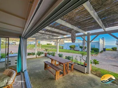 a patio with a wooden bench and a table at Seaside Charm in Gordonʼs Bay