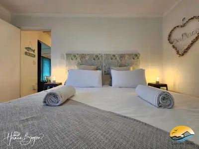 a bedroom with a large white bed with pillows at Seaside Charm in Gordonʼs Bay