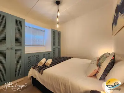 a bedroom with a bed with pillows and a window at Seaside Charm in Gordonʼs Bay