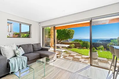 a living room with a couch and a view of the ocean at Zaria Sun Cottage in Gordonʼs Bay