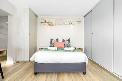 a bedroom with a large bed with white sheets at Zaria Sun Cottage in Gordonʼs Bay