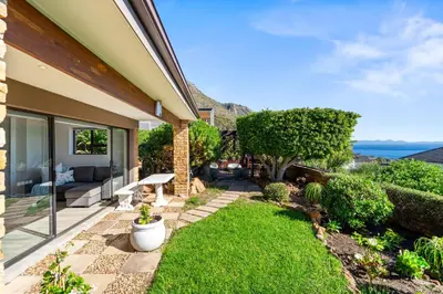 a backyard with a patio with a lawn at Zaria Sun Cottage in Gordonʼs Bay