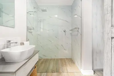 a white bathroom with a sink and a shower at Zaria Sun Cottage in Gordonʼs Bay
