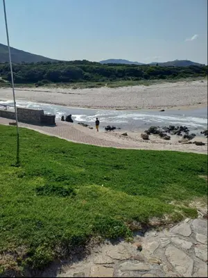 a person walking on a beach near the water at Dukes Place in Hermanus