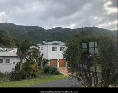 a white house with mountains in the background at Dukes Place in Hermanus