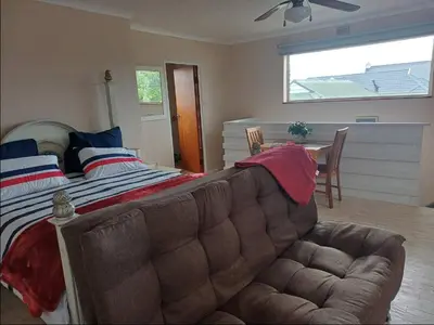 a bedroom with a large bed and a couch at Dukes Place in Hermanus