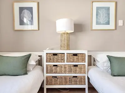 a bedroom with two beds and a table with a lamp at Strand Boat House in Cape Town