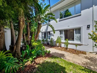 a white house with palm trees and a sidewalk at Strand Boat House in Cape Town