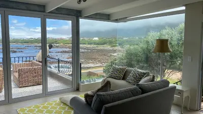 a living room with a view of the water at Onrus Sunset Beach House in Hermanus