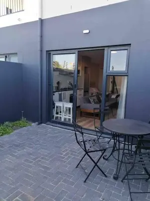 a patio with a table and chairs in a building at Blouberg Studio in Cape Town