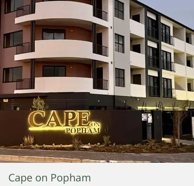 a large apartment building with a sign that reads cape on poplin at Blouberg Studio in Cape Town