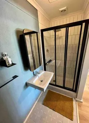 a bathroom with a sink and a shower with a mirror at Blouberg Studio in Cape Town