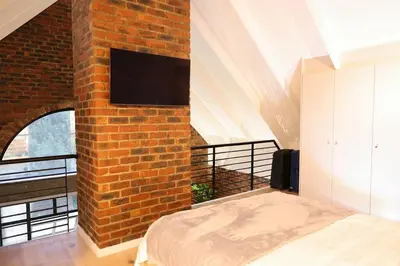 a bedroom with a brick wall with a bed and a tv at Tranquil Loft Design and Underground Parking in Stellenbosch