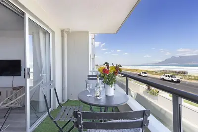 a table on a balcony with a view of a highway at Sea Spray B104 in Table View