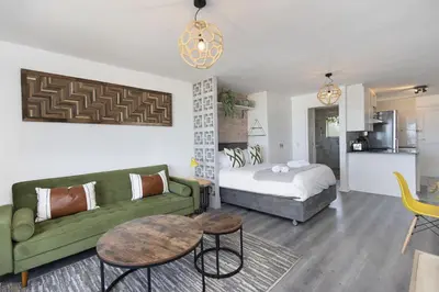 a living room with a green couch and a bed at Sea Spray B104 in Table View