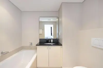 a white bathroom with a tub and a sink at Portico 405 in Bloubergstrand