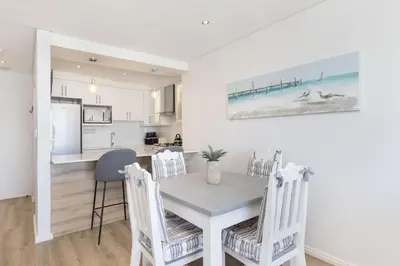 a kitchen and dining room with a table and chairs at Portico 704 in Bloubergstrand