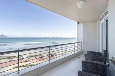 a balcony with chairs and a view of the beach at Portico 704 in Bloubergstrand