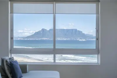 a window with a view of the ocean and a mountain at Portico 704 in Bloubergstrand