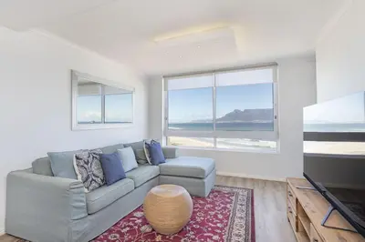 a living room with a couch and a table at Portico 704 in Bloubergstrand